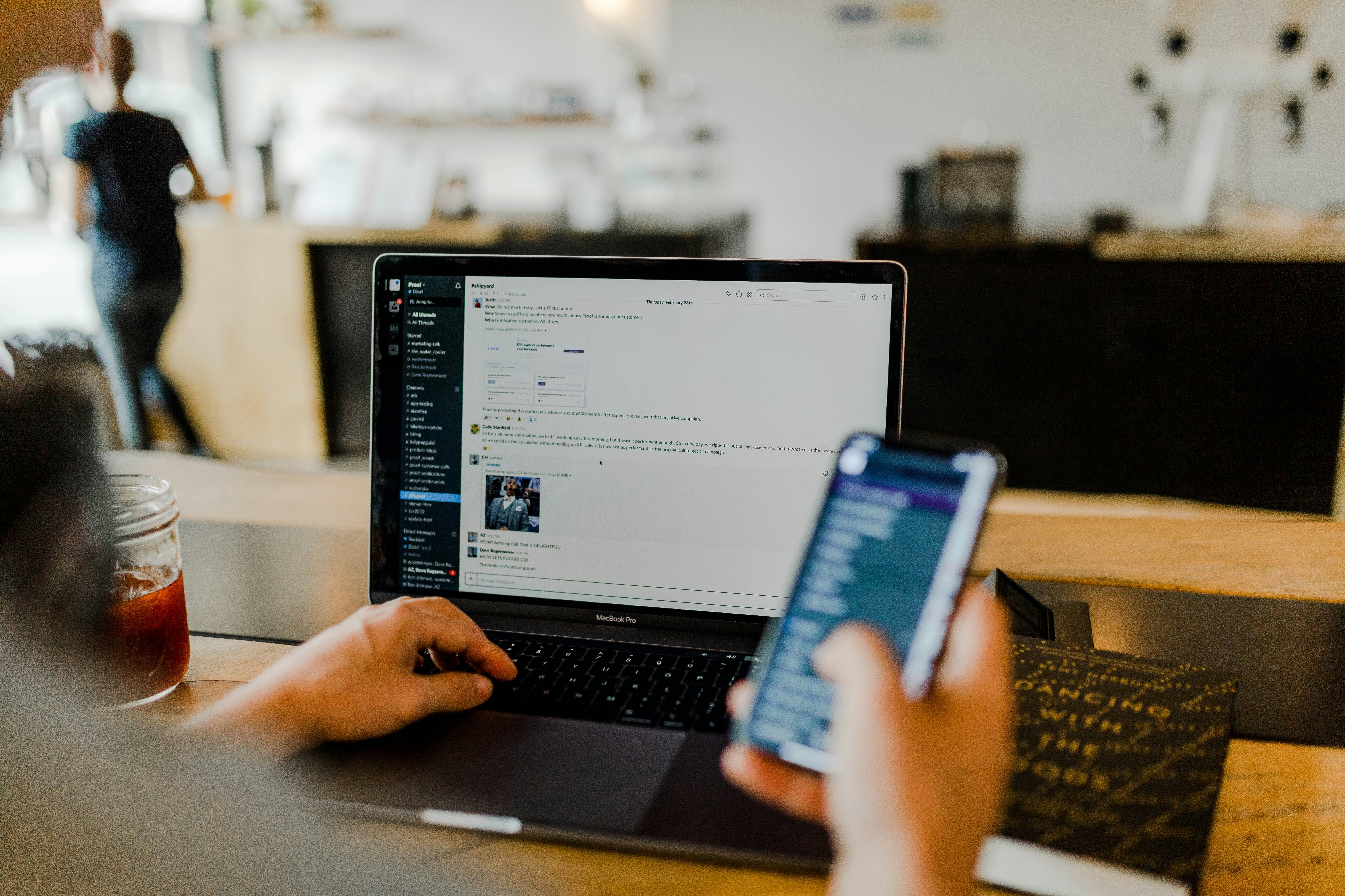 A person using a phone and a laptop, planning a Labor Day email campaign before the long weekend