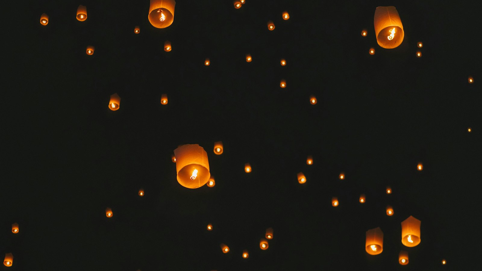 Many sky lanterns floating in the dark night sky